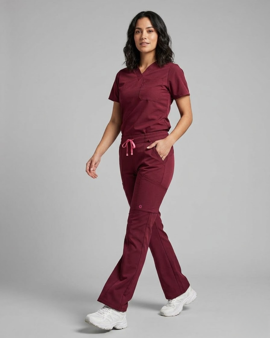 Woman wearing a maroon scrub set on a gray background
