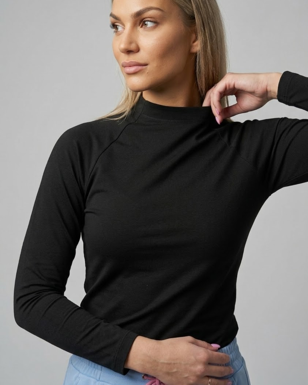 Woman wearing a black long-sleeve top against a gray background