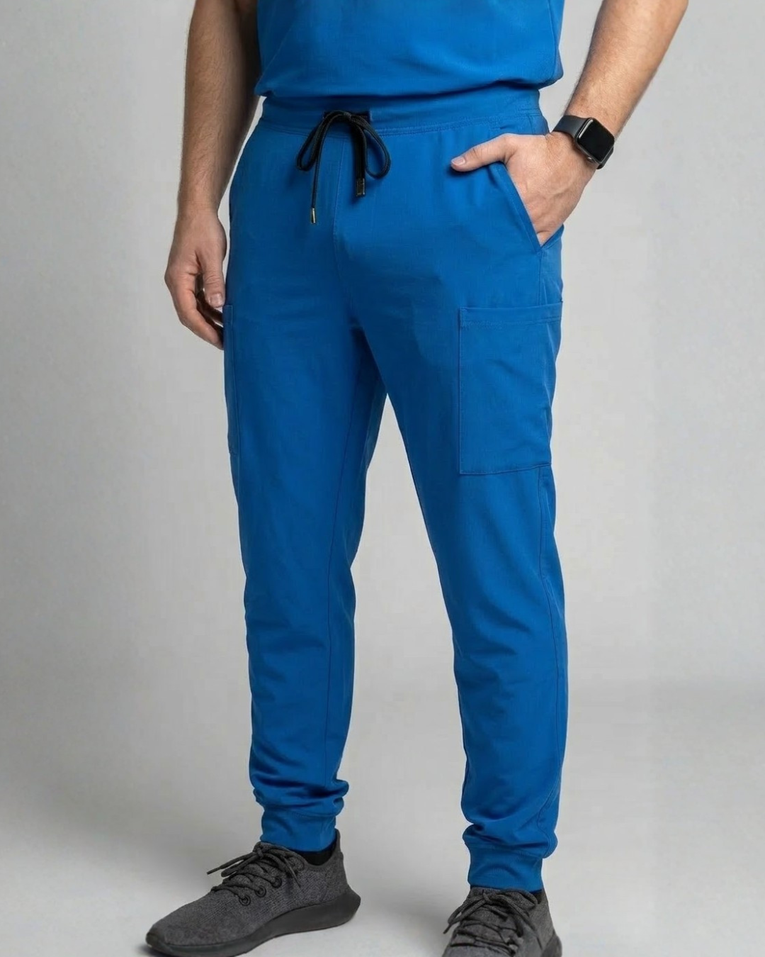 Person wearing blue jogger pants and a matching top on a plain background
