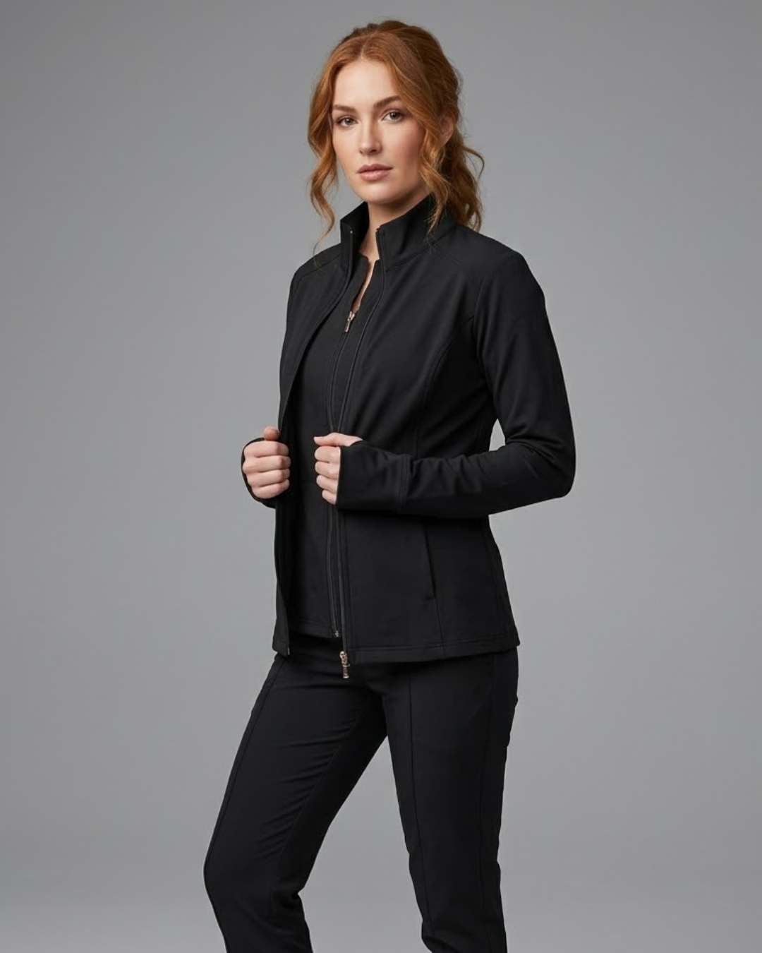 Woman wearing a black jacket and pants against a gray background