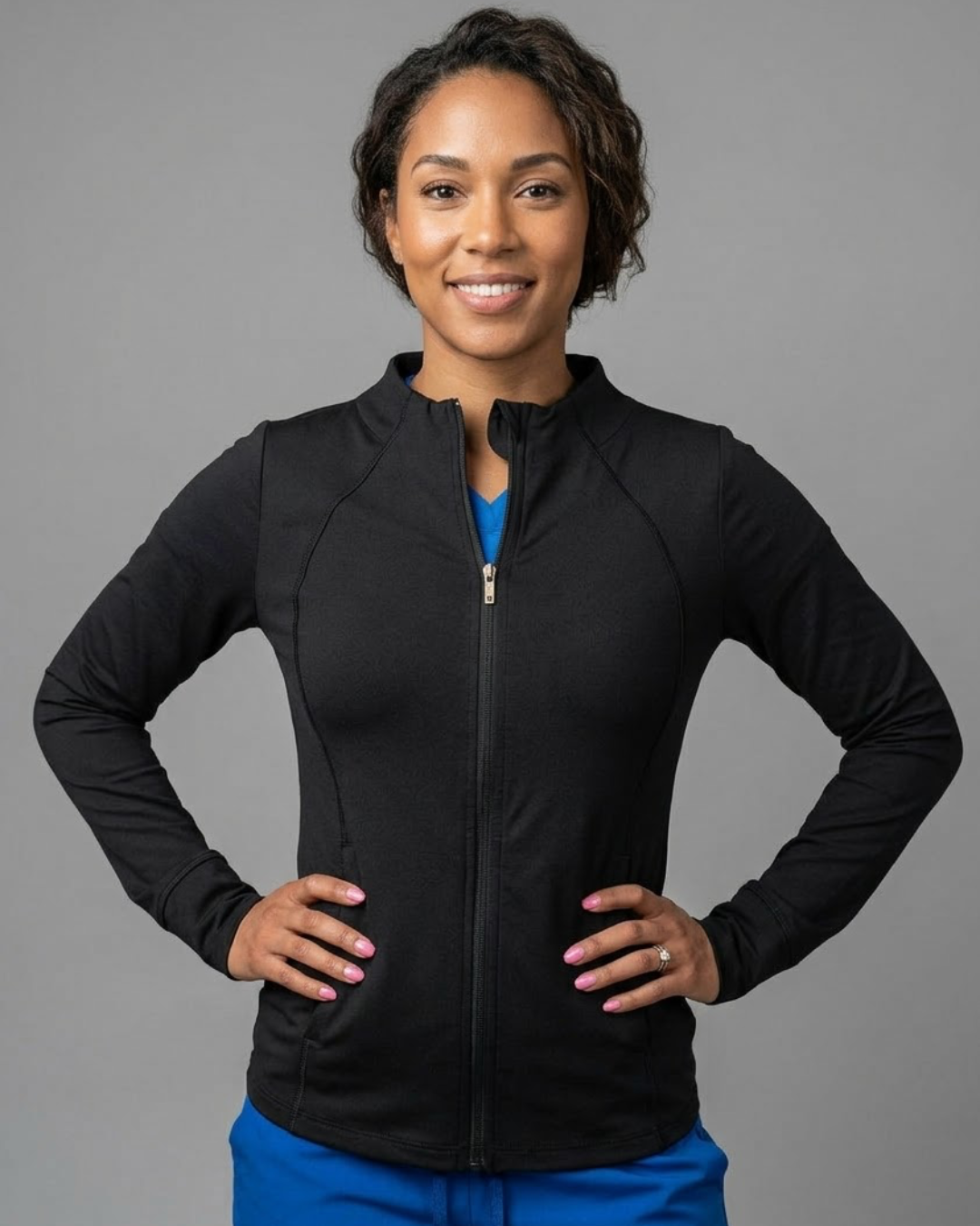 Woman wearing a black jacket over a blue shirt on a gray background